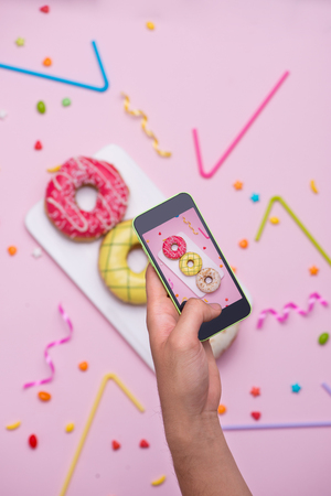 Party. Taking photo of different colourful sugary round glazed donutsの写真素材