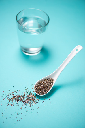 Glass of water and healthy chia seeds in a spoon. Text space.の写真素材