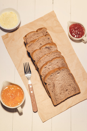 Close-up of slice of toast bread with jam and butter on wood tableの写真素材