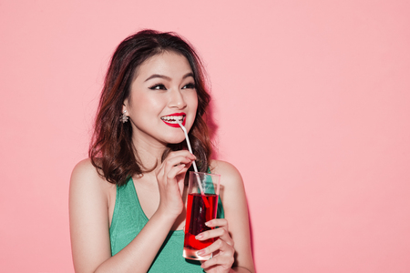 Happy fashion asian woman drinking champagne over pink background.の写真素材