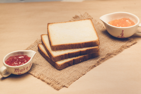 Toast with strawberry and orange jam on a plate on table.の写真素材