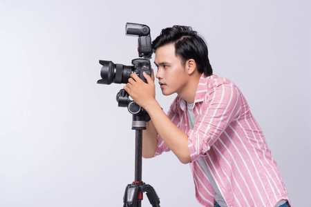 Young asian photographer holding digital camera, while working in studioの写真素材