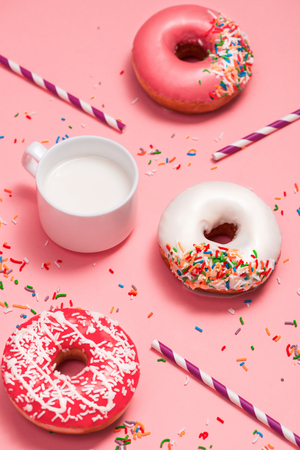 Donuts with icing and milk on pastel pink background. Sweet donuts.の写真素材