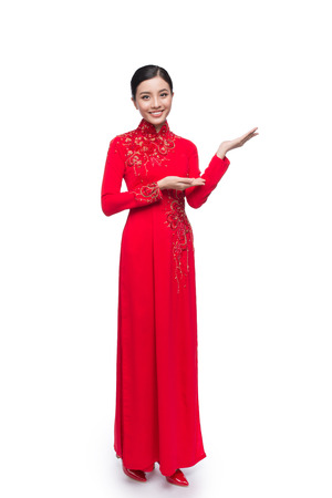 Full body of charming Vietnamese Woman in Ao Dai Traditional Dress present somethingの写真素材
