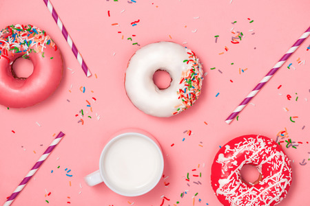 Donuts with icing and milk on pastel pink background. Sweet donuts.の写真素材