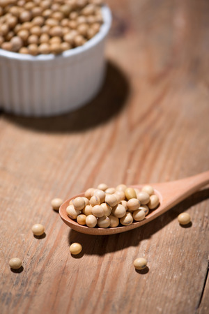 Soya beans in spoon on wooden table.の写真素材