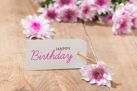 Blank white tag paper with color flowers on wooden background. Top view. Mock upの写真素材