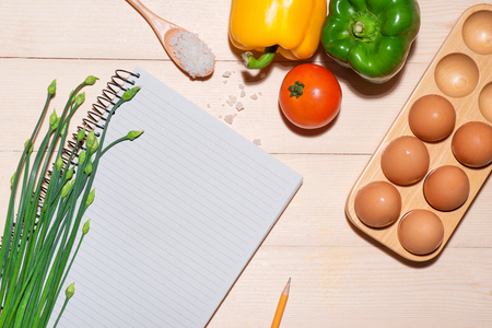 Open recipe book with fresh vegetables on wooden table.の写真素材