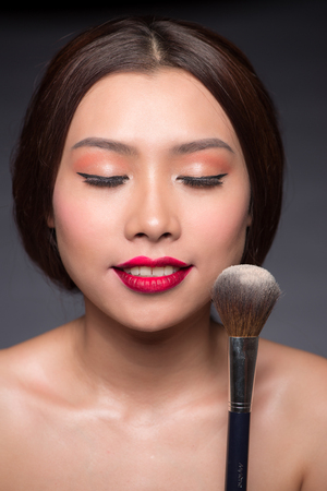 Beautiful asian woman face with perfect makeup  applying dry cosmetic.の写真素材