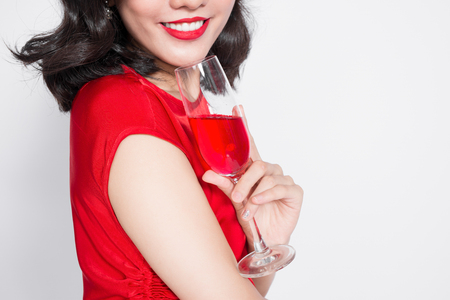 Cropped images of young celebrating asian woman in red dress holding wine glass.の写真素材