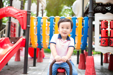 Happy asian boy playing seesaw at the playground in the parkの写真素材