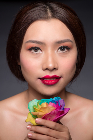 Beautiful asian woman face with perfect makeup with flowers of a roseの写真素材