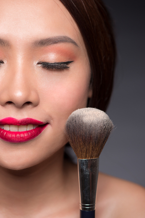 Beautiful asian woman face with perfect makeup  applying dry cosmetic.の写真素材
