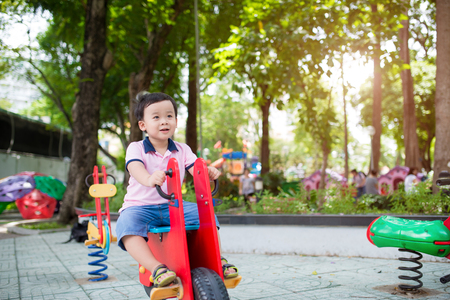 Happy asian boy playing seesaw at the playground in the parkの写真素材