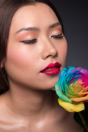 Beautiful asian woman face with perfect makeup with flowers of a roseの写真素材