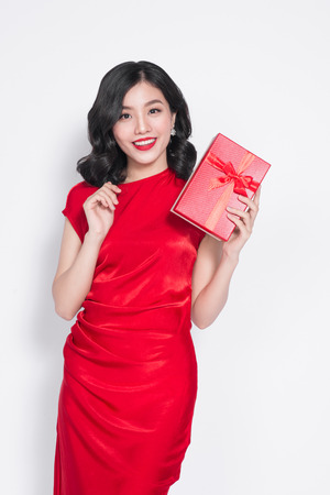Pretty young glamorous asian woman dressed in red dress with a presentの写真素材