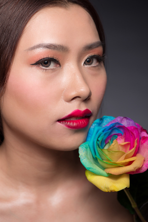 Beautiful asian woman face with perfect makeup with flowers of a roseの写真素材