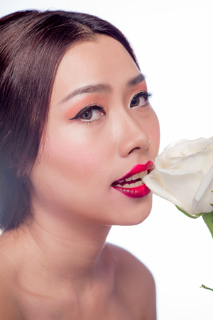 Beautiful asian woman face with perfect makeup with flowers of a roseの写真素材