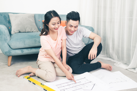 Attractive young asian adult couple looking at house plans.の写真素材