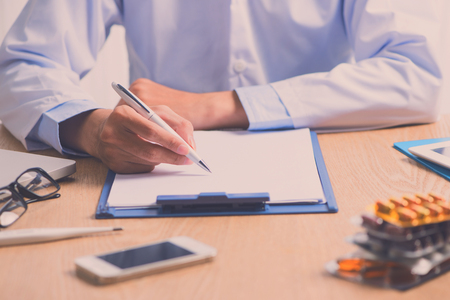 Male doctor working at wooden desk in clinicの写真素材