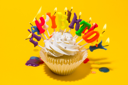 Birthday cupcake with  candle on yellow background.の写真素材