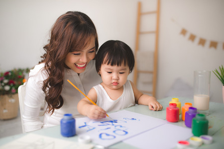 Happy family mother and daughter together paint. Asian woman helps her child girl.の写真素材