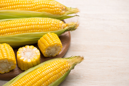 Sweet corn on cobs on cutting board on wooden table.の写真素材