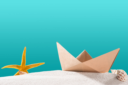 Boat paper origami on sand isolated on blue.の写真素材