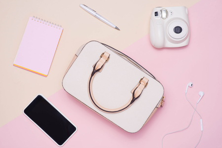 Flat lay of female fashion accessories and white handbag on pastel color background with copyspaceの写真素材