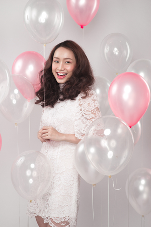 Asian pretty fashionable woman in white dress with pastel balloonsの写真素材