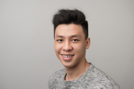 Portrait of good looking asian man over gray background.の写真素材