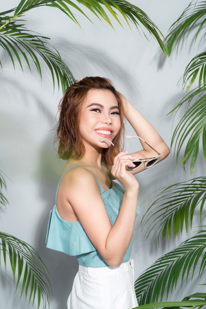 Beauty summer. Beautiful asian woman between palm leaves.の写真素材