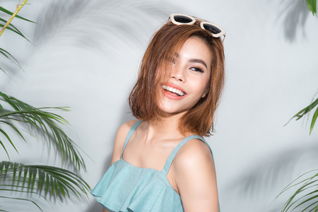 Beauty summer. Beautiful asian woman between palm leaves.の写真素材
