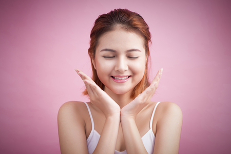 Portrait of attractive Vietnamese woman touching her face on pink background.の写真素材