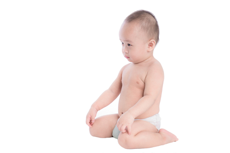 Portrait of a cute cheerful little boy sitting on floor, isolated over whiteの写真素材