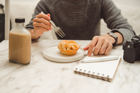 Close up of male hands with notebook, muffin and coffee cup on tableの写真素材