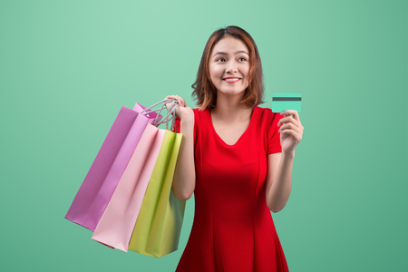Santa asian woman holding shopping bags and credit card against blue vignetteの写真素材