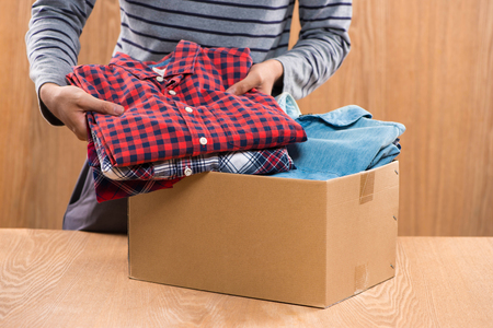 Donation box for poor with clothing in male handsの写真素材