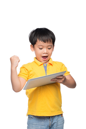 Portrait of cheerful boy with backpack holding digital tablet with hand raisedの写真素材