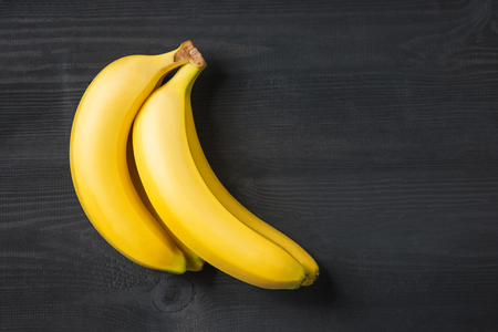 A banch of bananas and a sliced banana in a dish over yellow backgroundの写真素材