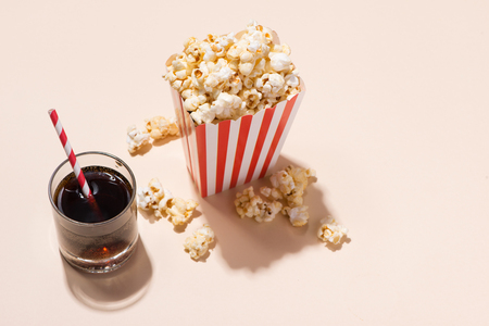 Popcorn in red and white cardboard with glass of sodaの写真素材