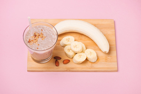 Fresh made banana smoothie in a glass on pink backgroundの写真素材