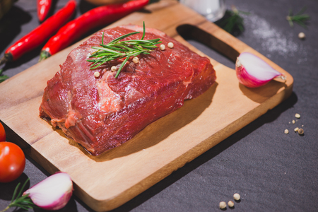 Raw beef on a cutting board  with spices and ingredients for cooking.の写真素材