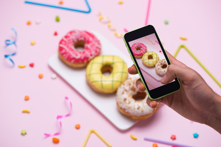 Party. Taking photo of different colourful sugary round glazed donutsの写真素材