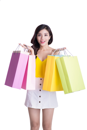 Asian smiling young woman holding colorful paper bags. Concept for shop sales. Isolated on white backgroundの写真素材