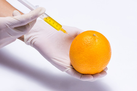 Science experiment with orange and syringe isolated on white.の写真素材