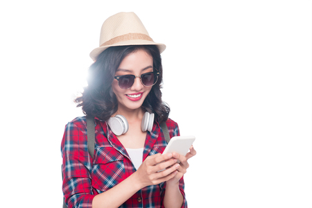 Happy young asian woman using smartphone standing isolated on white.の写真素材