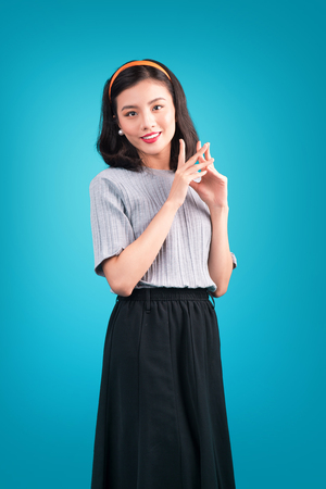 Smiling lovely asian woman dressed in pin-up style dress over blue.の写真素材
