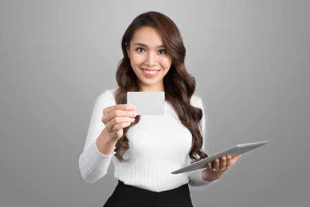 Confident young asian woman holding digital tabler showing credit card.の写真素材