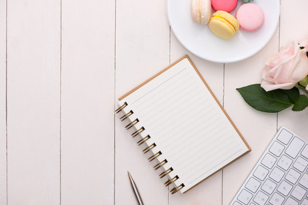 White desk with colorful macaroons, keyboard and open notebook.の写真素材
